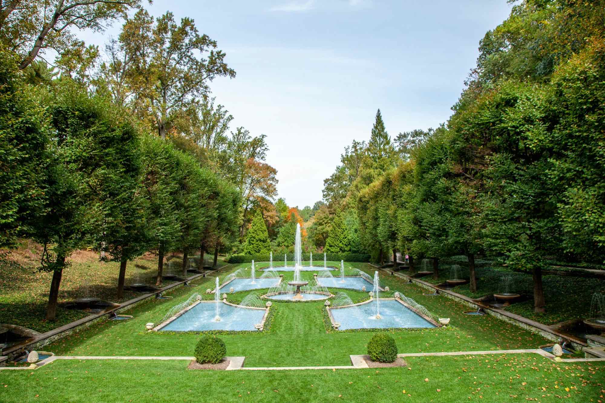 An Italian water garden of turquoise pools and fountains between tall clipped trees